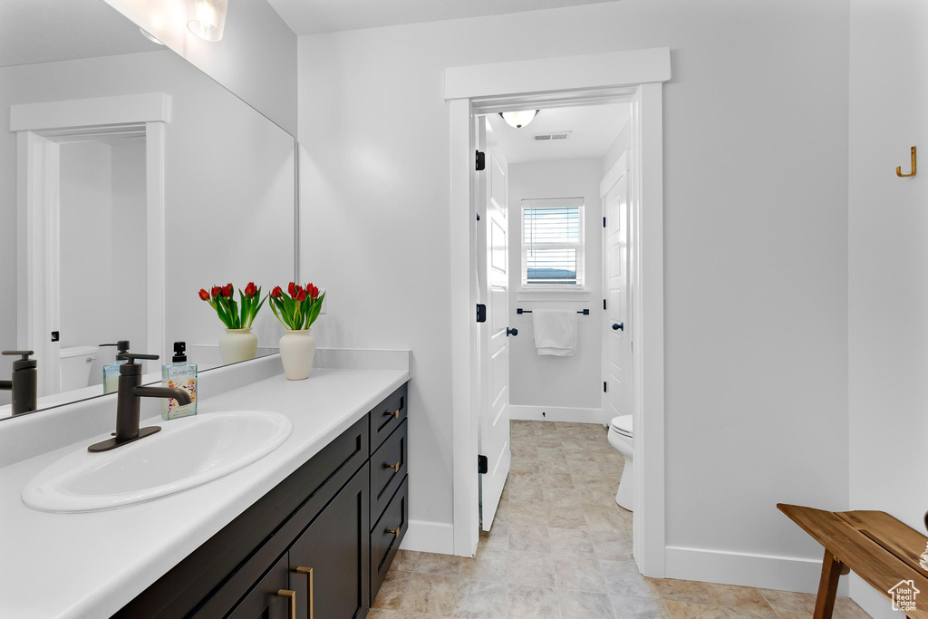 Bathroom with vanity, toilet, and baseboards