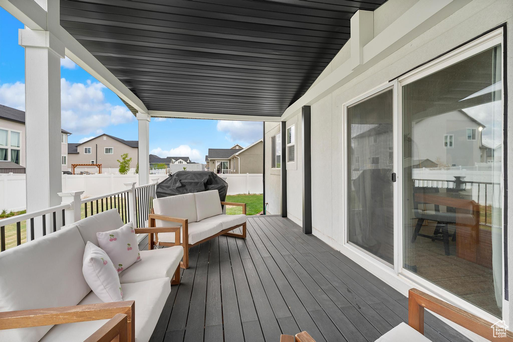 Wooden terrace featuring outdoor lounge area, a fenced backyard, a residential view, and a grill