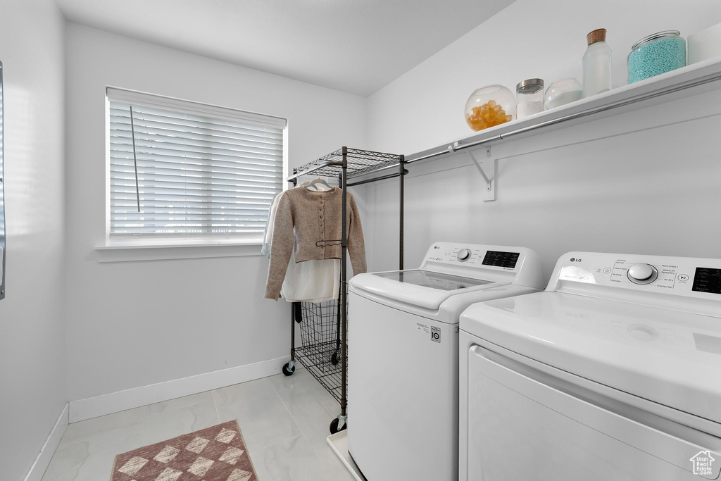 Laundry area featuring washing machine and clothes dryer, baseboards, and light marble finish floors
