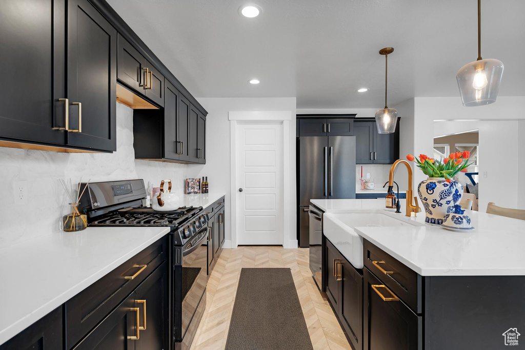 Kitchen featuring range with gas cooktop, a sink, recessed lighting, light countertops, and an island with sink