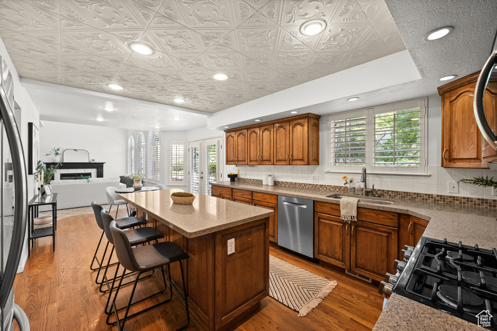 Kitchen featuring a sink, appliances with stainless steel finishes, an ornate ceiling, a center island, and healthy amount of natural light