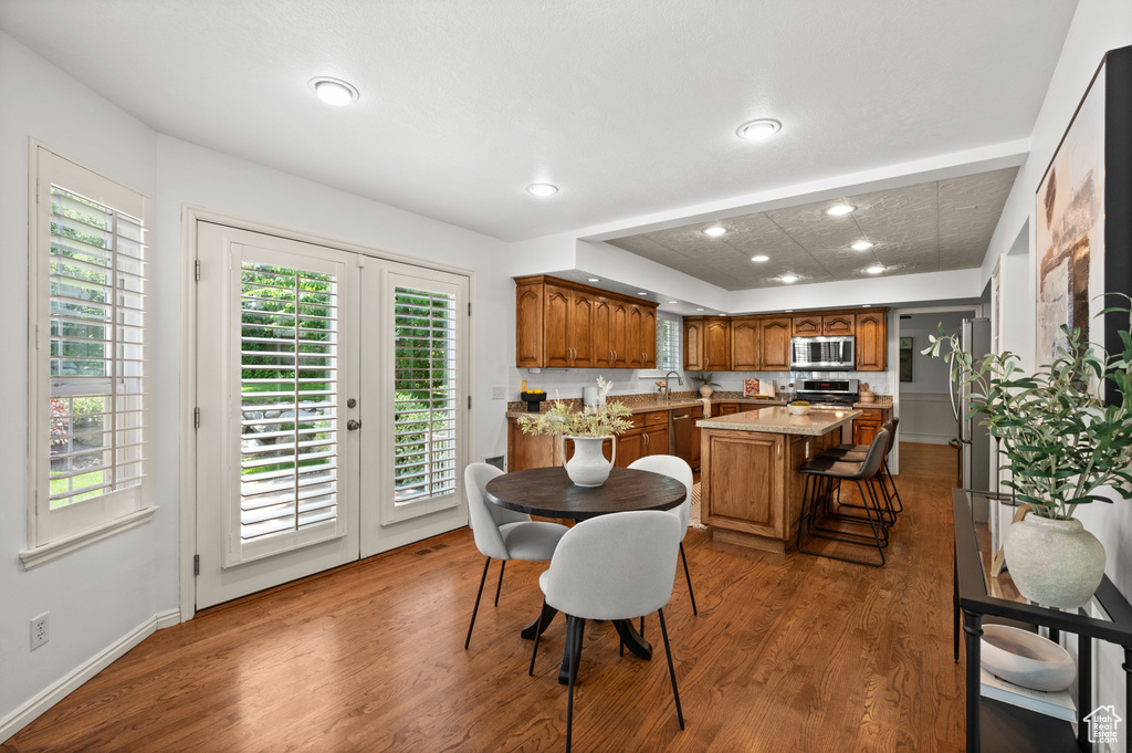 Dining room with wood finished floors, healthy amount of natural light, recessed lighting, and french doors