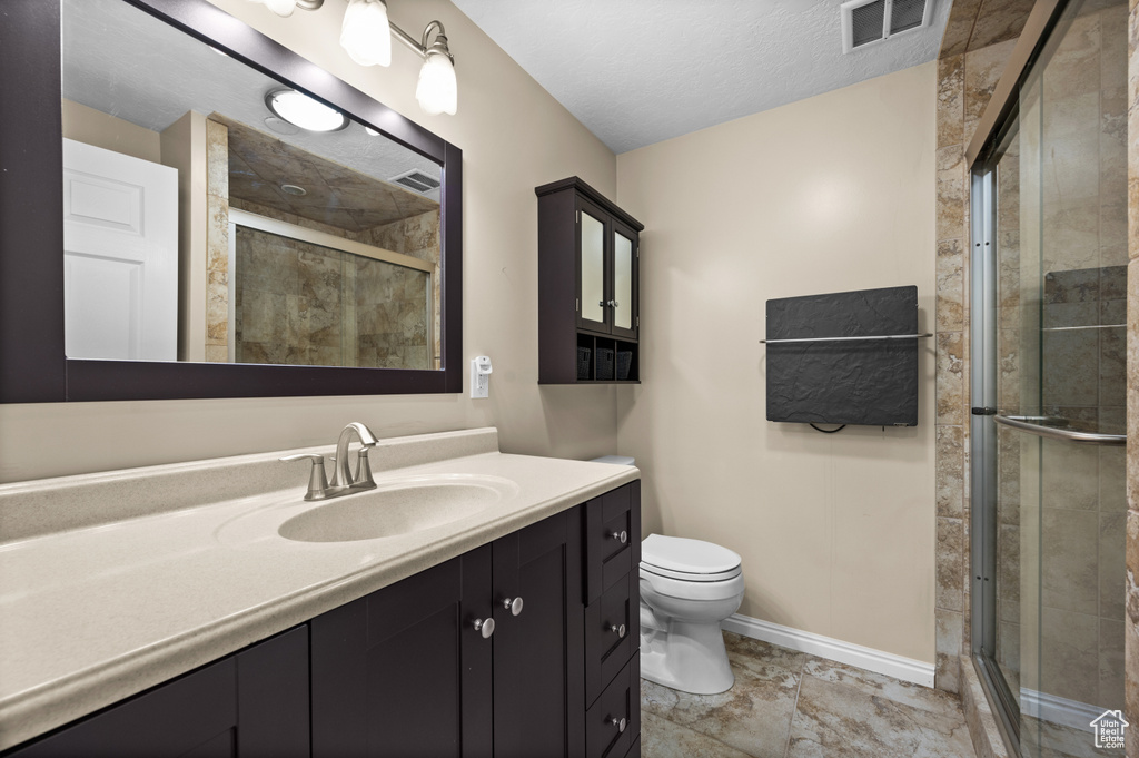 Full bathroom featuring vanity, toilet, a shower stall, and baseboards