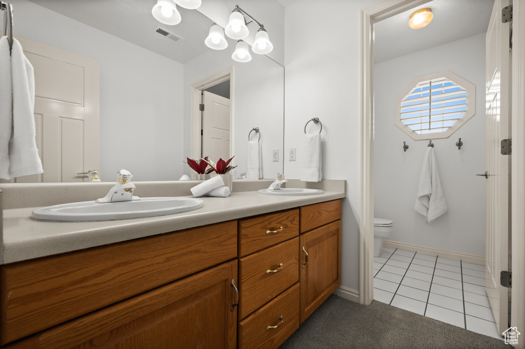 Full bath with double vanity, toilet, tile patterned floors, and baseboards