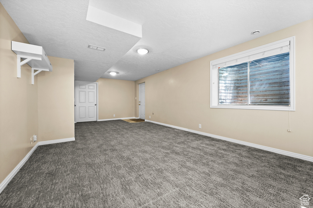 Carpeted empty room with baseboards and a textured ceiling