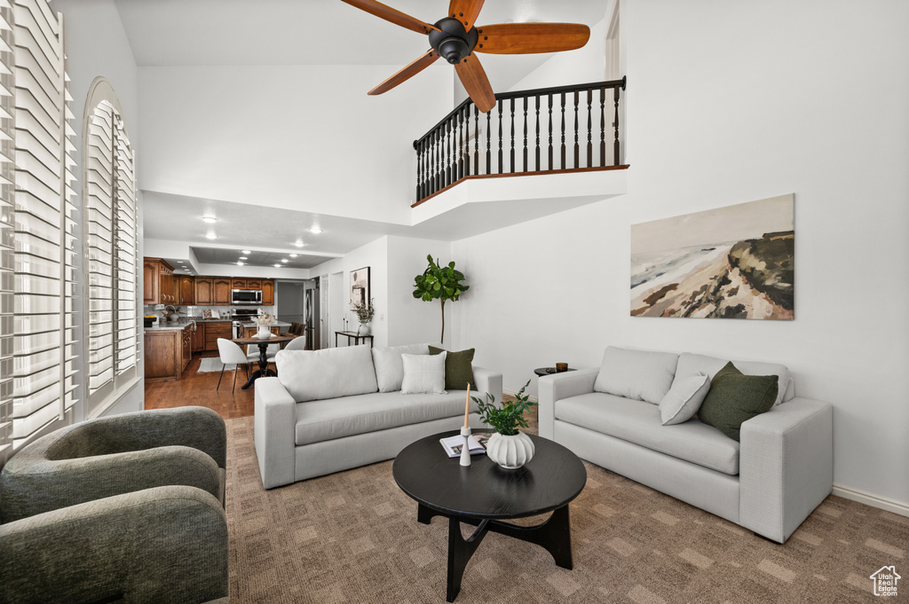 Living area featuring a towering ceiling, ceiling fan, and baseboards