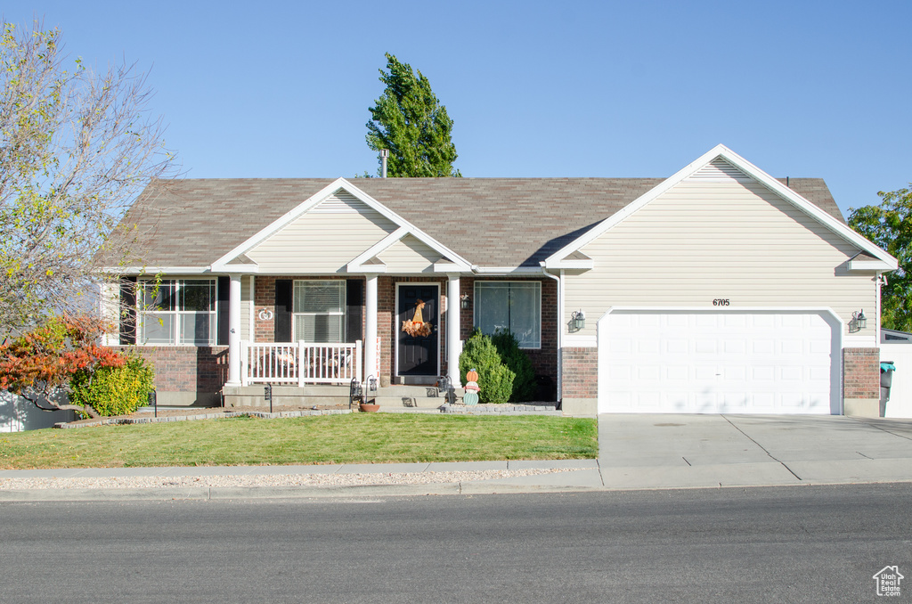 View of front facade featuring a porch, brick siding, a garage, and driveway