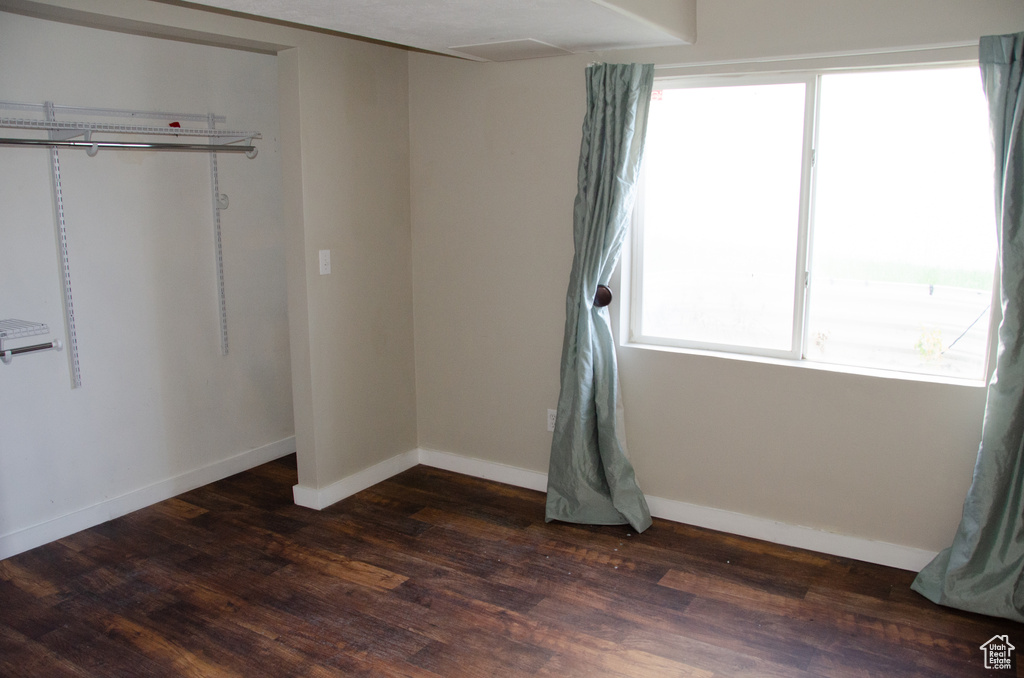 Unfurnished bedroom featuring dark wood-style flooring and baseboards