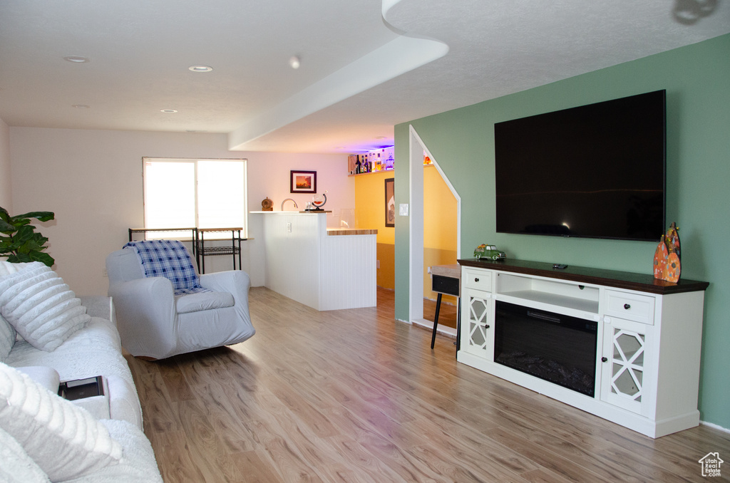 Living area with light wood-type flooring and recessed lighting