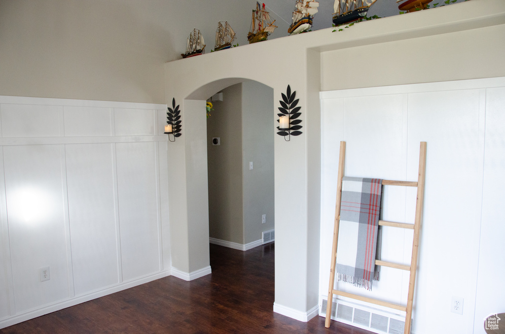 Empty room with arched walkways and dark wood-style floors