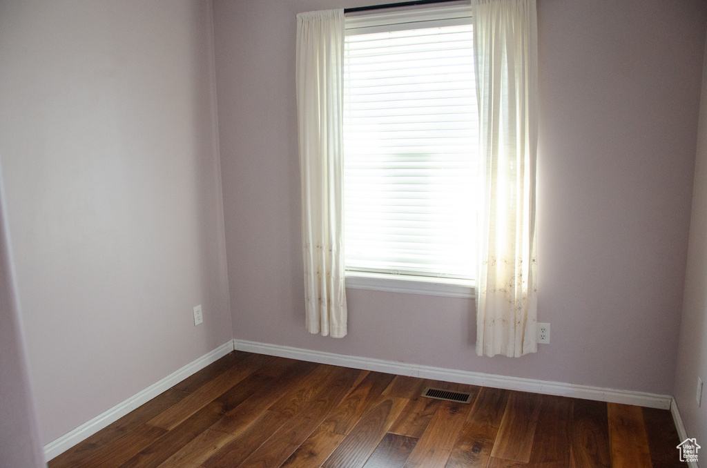 Unfurnished room with baseboards, dark wood-style floors, and plenty of natural light