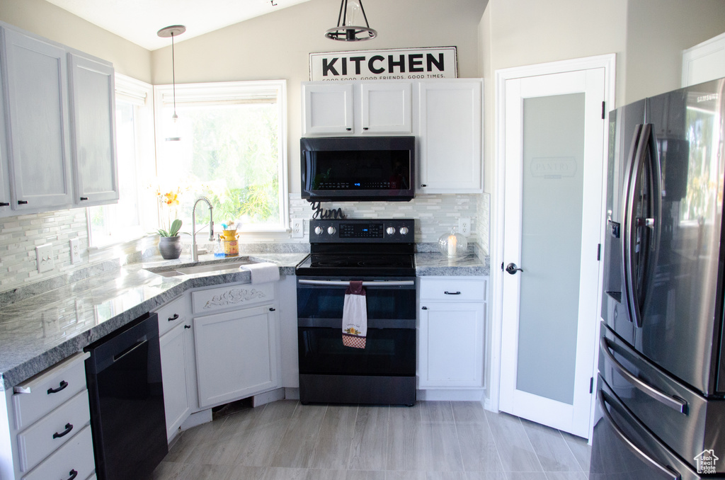Kitchen featuring stainless steel fridge with ice dispenser, range with electric stovetop, black dishwasher, a sink, and white cabinetry