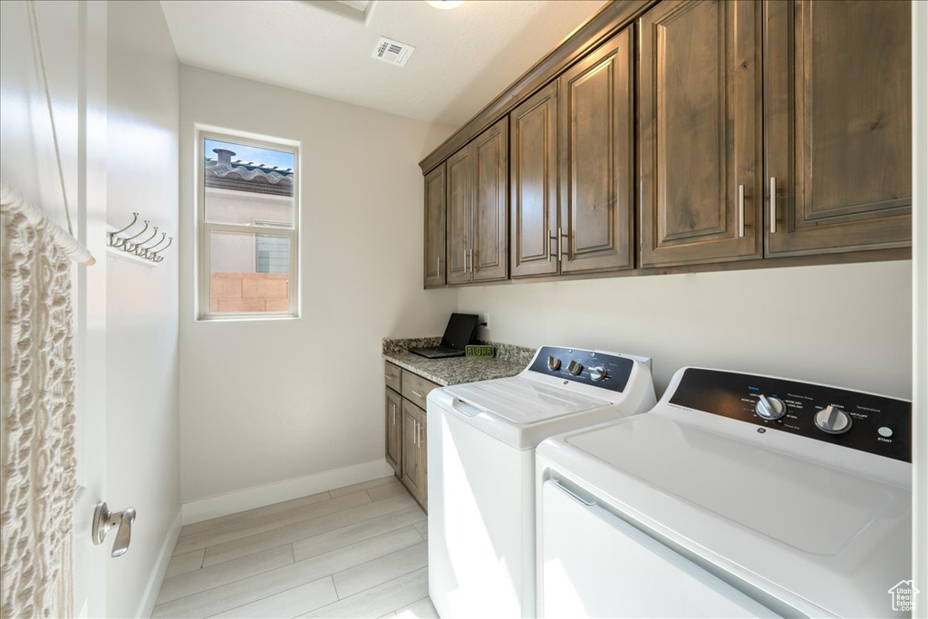 Washroom with independent washer and dryer, cabinet space, baseboards, and wood finish floors