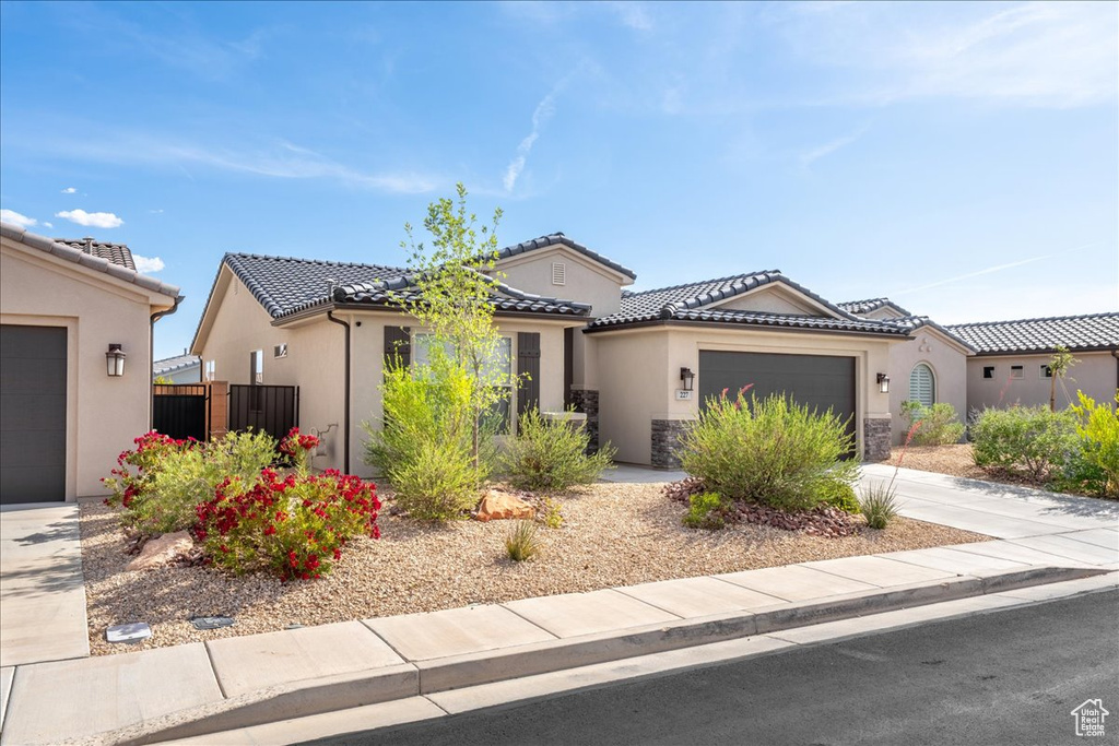 View of front of property featuring stucco siding, a garage, concrete driveway, a tiled roof, and stone siding