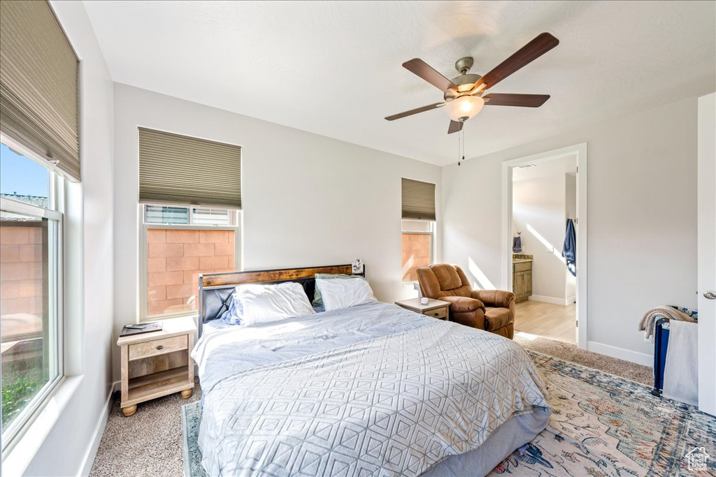 Bedroom with baseboards, carpet, ceiling fan, and ensuite bath