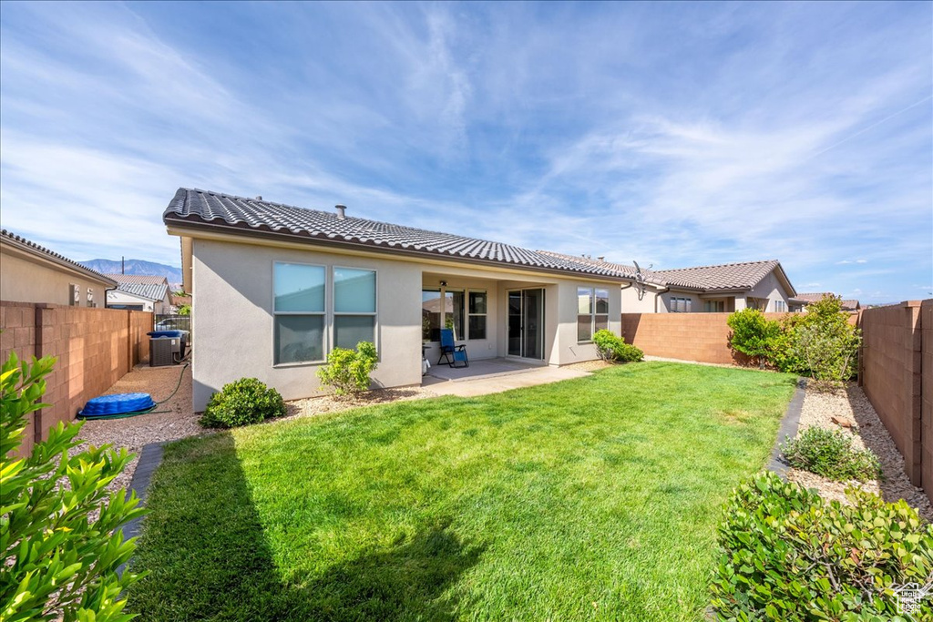 Back of property with stucco siding, a tiled roof, a patio area, and central AC