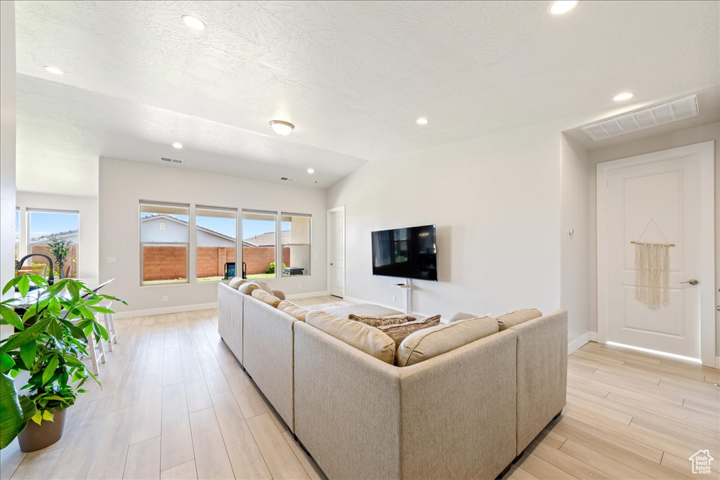 Living room featuring baseboards, healthy amount of natural light, light wood finished floors, and recessed lighting