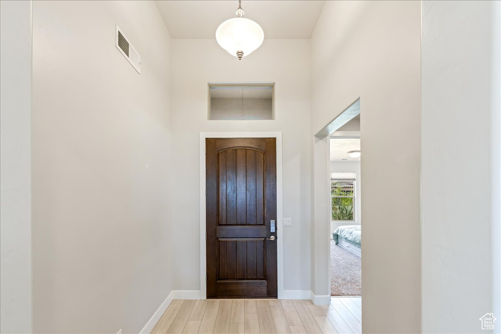 Entryway with light wood-style flooring, baseboards, and a towering ceiling
