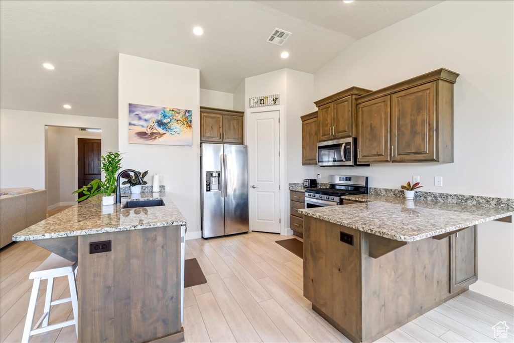 Kitchen with stainless steel appliances, a peninsula, a sink, a kitchen breakfast bar, and recessed lighting