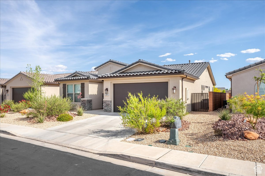 View of front of home with a garage, stucco siding, driveway, and a tiled roof