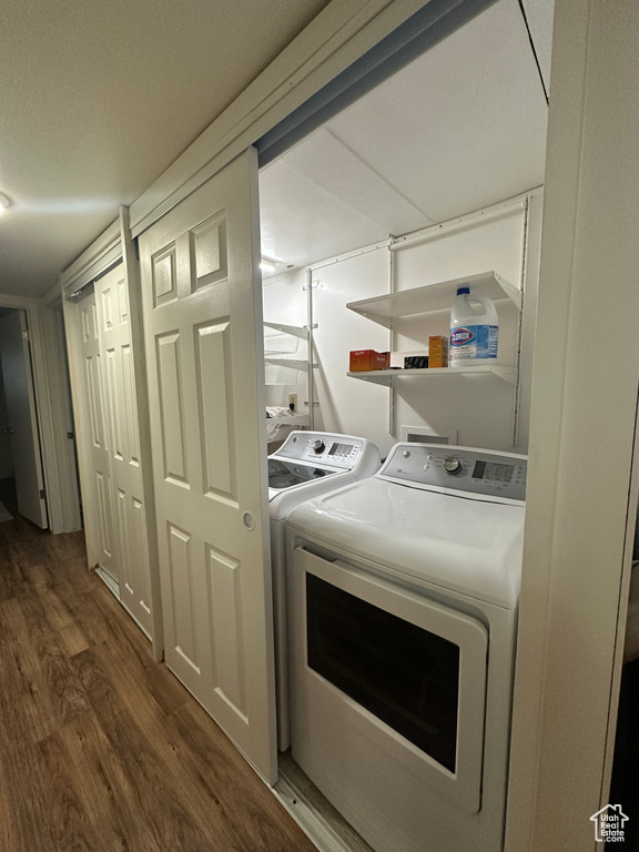 Laundry area with washing machine and clothes dryer and wood finished floors