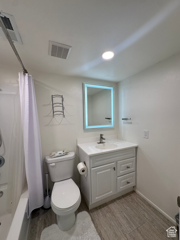 Full bathroom featuring vanity, toilet, wood finished floors, and shower / bath combination with curtain