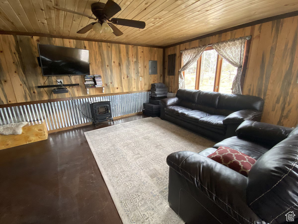 Living room featuring wooden walls, wooden ceiling, a ceiling fan, and a wood stove