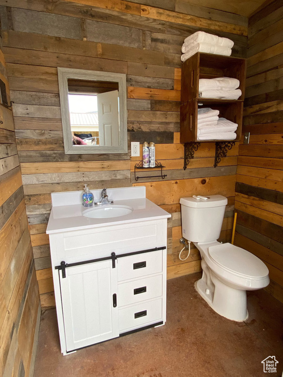 Bathroom with wood walls, vanity, and toilet