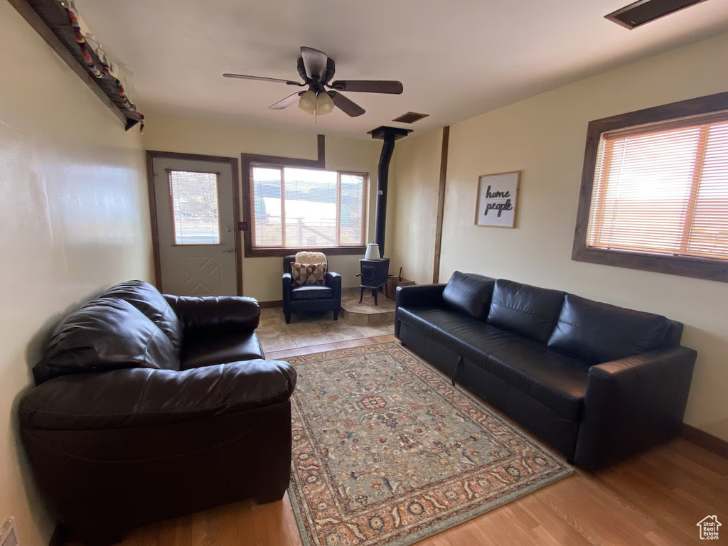 Living area featuring a wood stove, a ceiling fan, wood finished floors, and baseboards