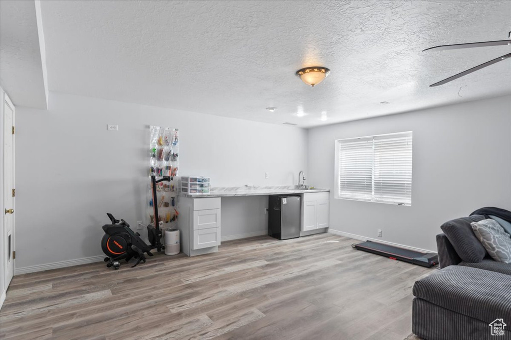 Interior space with refrigerator, light wood-type flooring, baseboards, a sink, and a textured ceiling