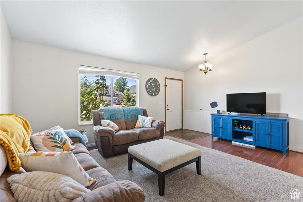 Living area featuring a chandelier, dark wood-type flooring, and lofted ceiling