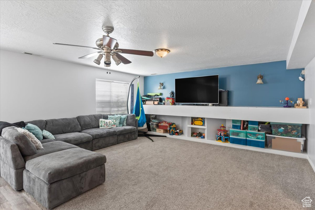 Living area featuring a textured ceiling, a ceiling fan, and carpet floors