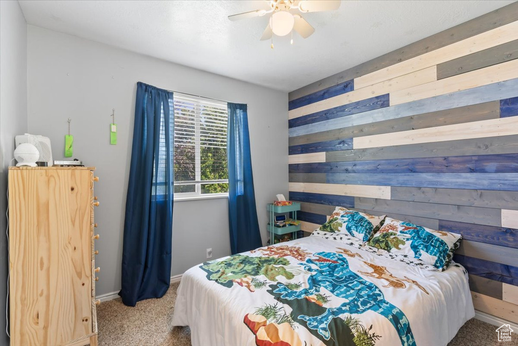 Bedroom featuring wooden walls, carpet flooring, baseboards, and ceiling fan