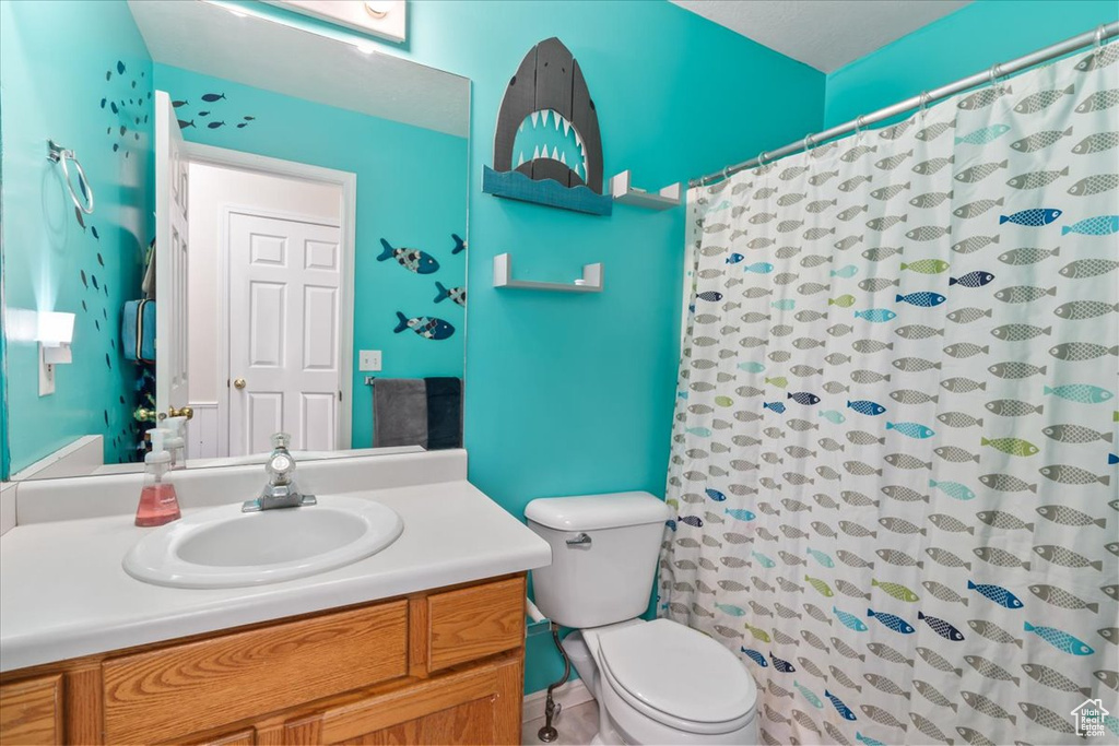 Full bath with toilet, vanity, and curtained shower