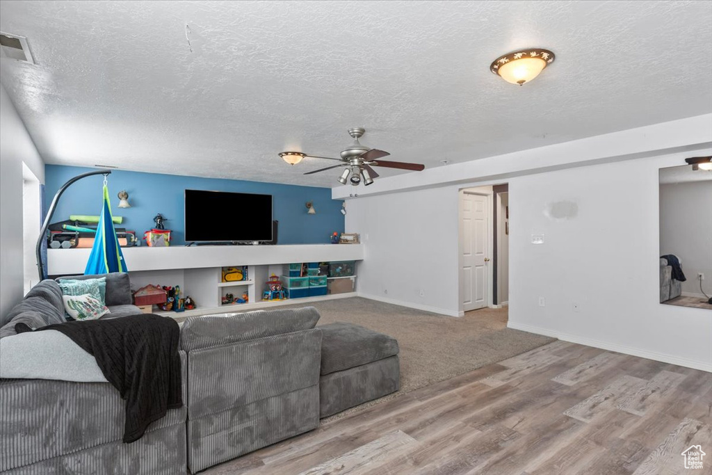 Living area with ceiling fan, wood finished floors, a textured ceiling, and baseboards