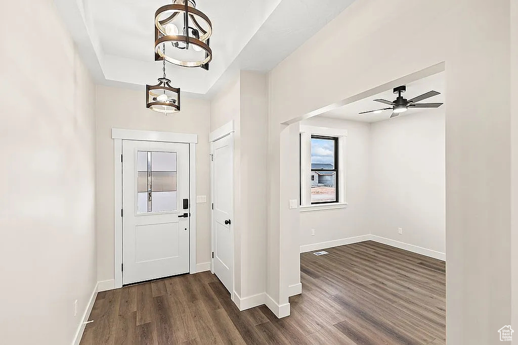 Entryway featuring dark wood-type flooring, baseboards, ceiling fan, and a chandelier