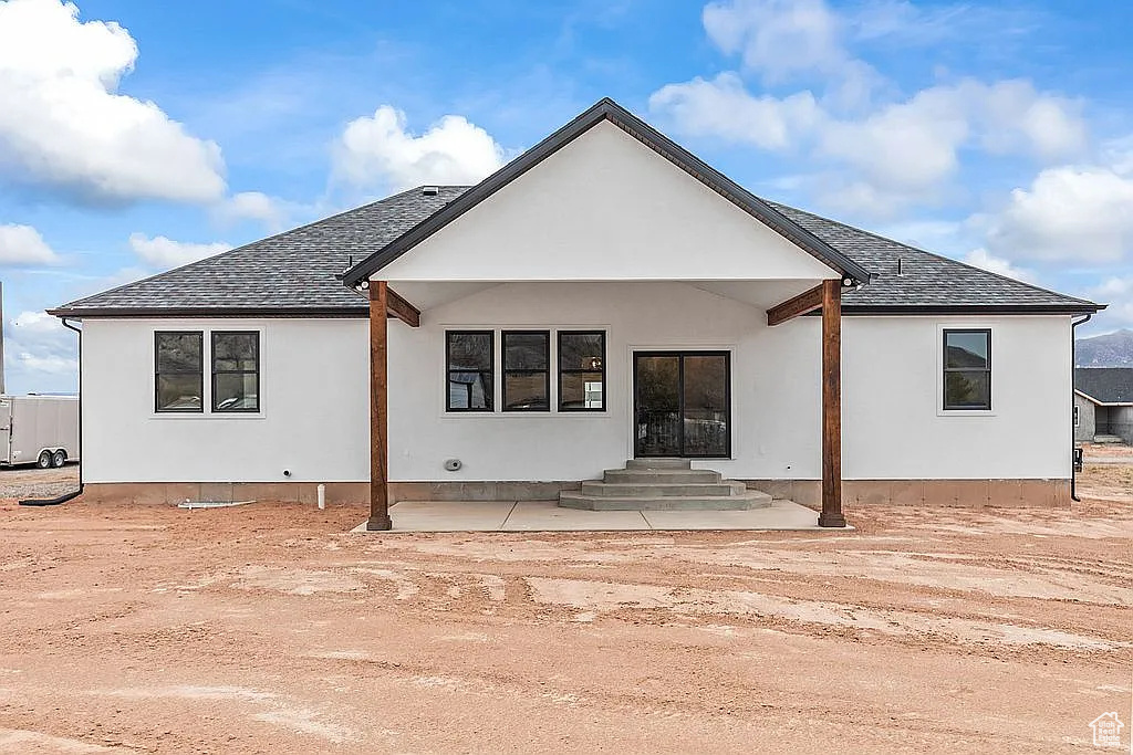 Back of property featuring stucco siding, a shingled roof, and entry steps