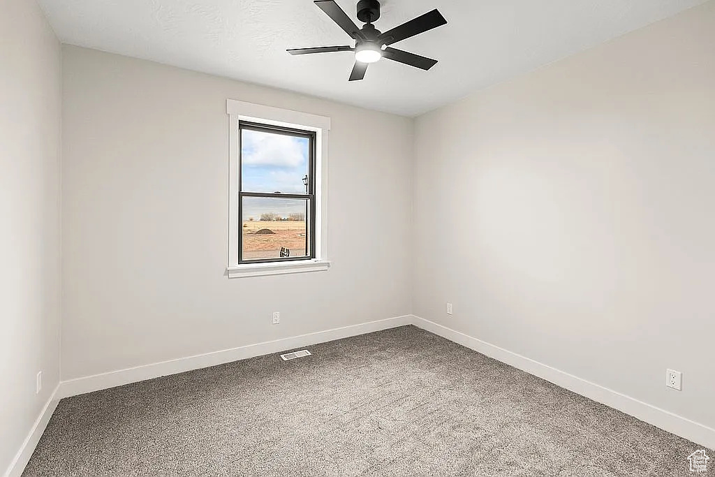 Carpeted spare room featuring baseboards and a ceiling fan