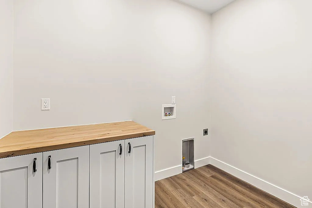 Washroom featuring washer hookup, electric dryer hookup, wood finished floors, baseboards, and cabinet space