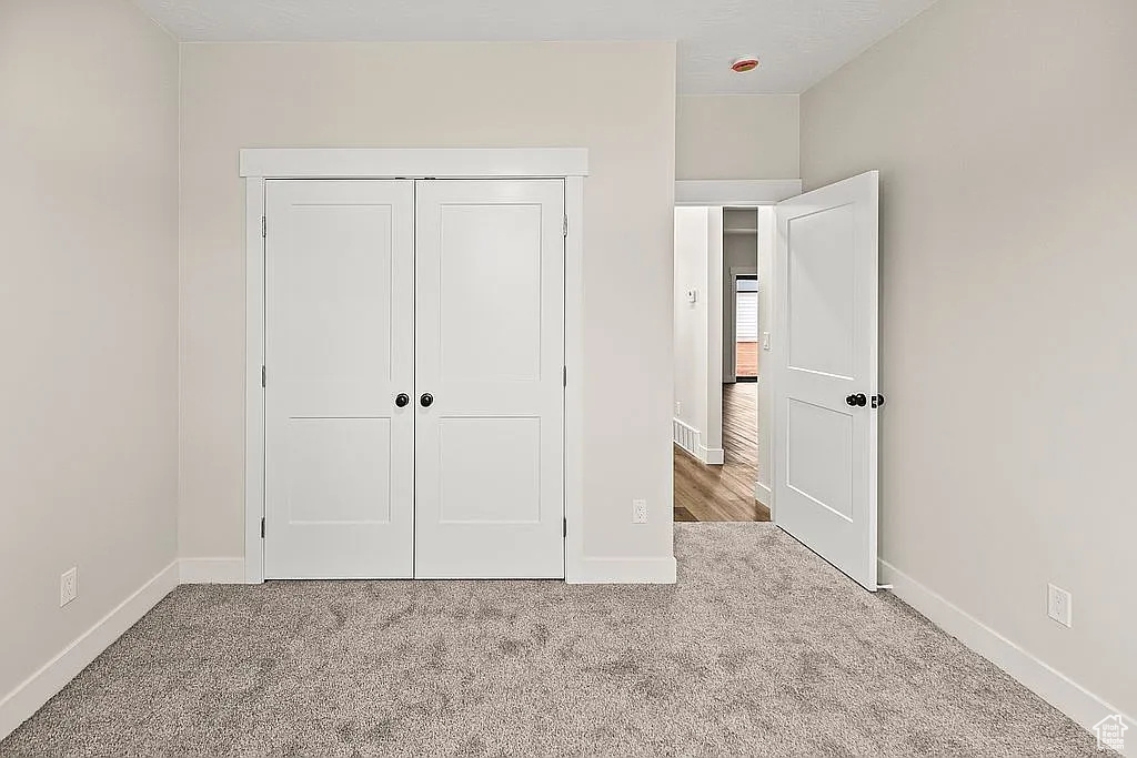 Unfurnished bedroom with carpet, baseboards, and a closet