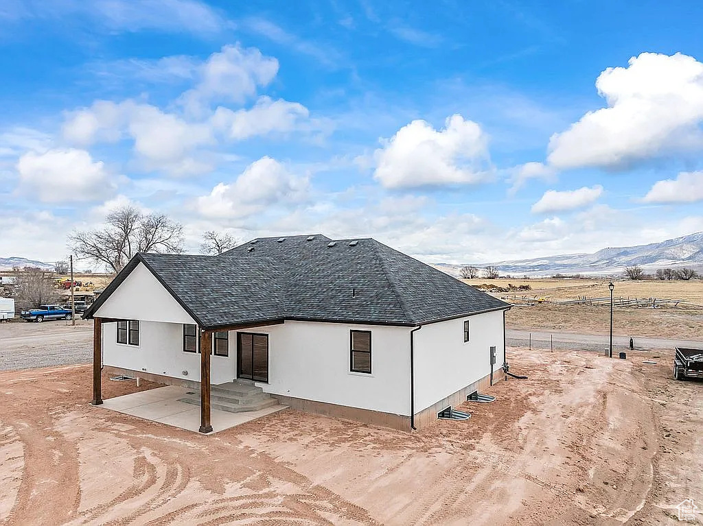 Rear view of house with stucco siding, roof with shingles, and a mountain view