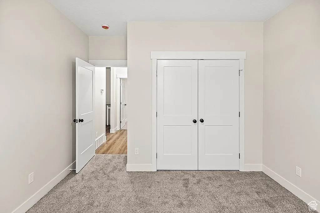 Unfurnished bedroom with carpet, baseboards, and a closet