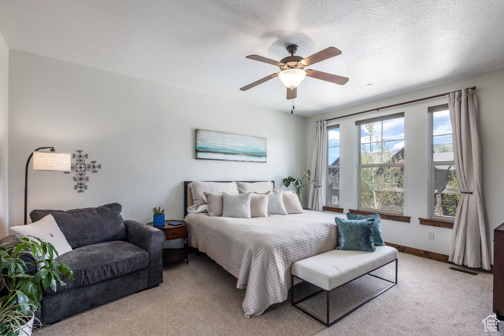 Bedroom with light carpet, a ceiling fan, a textured ceiling, and baseboards