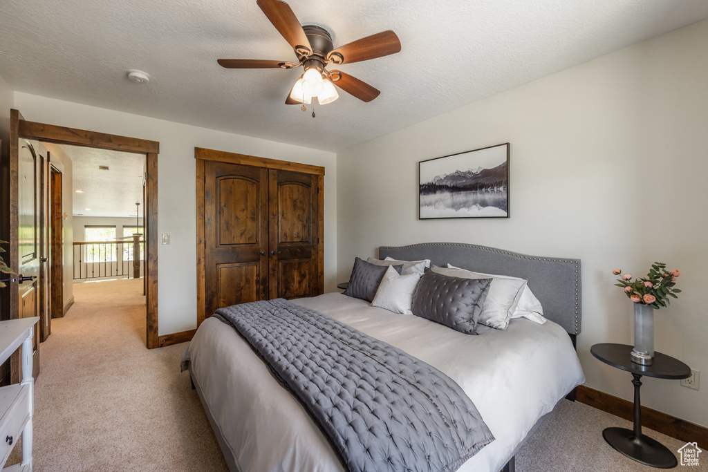 Bedroom featuring light colored carpet, baseboards, a closet, and a ceiling fan