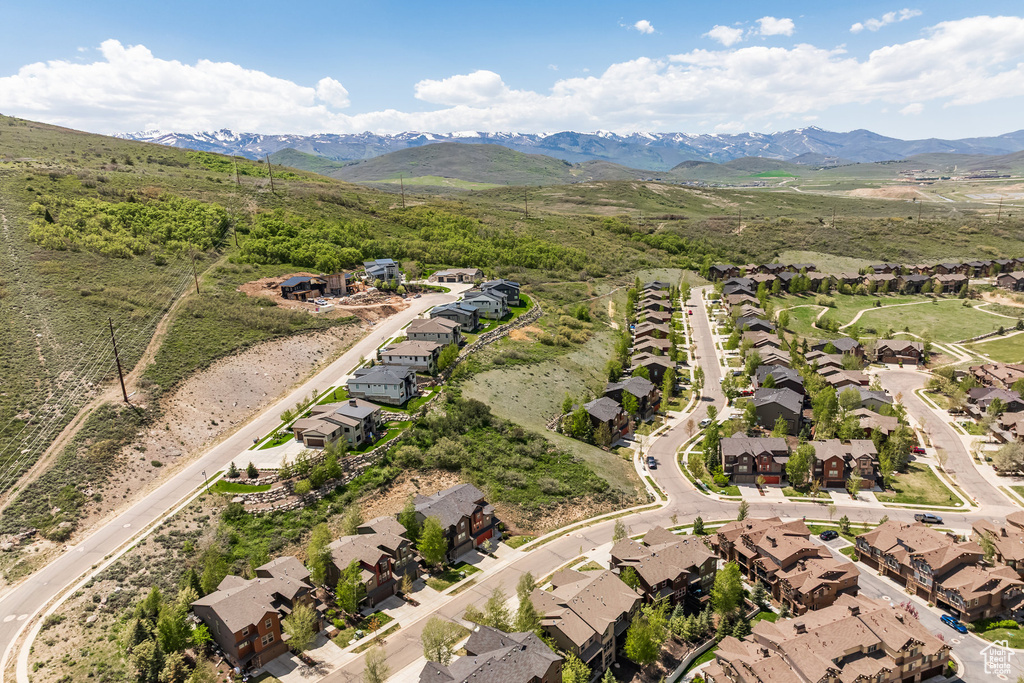 Aerial view of property and surrounding area featuring nearby suburban area and a mountainous background