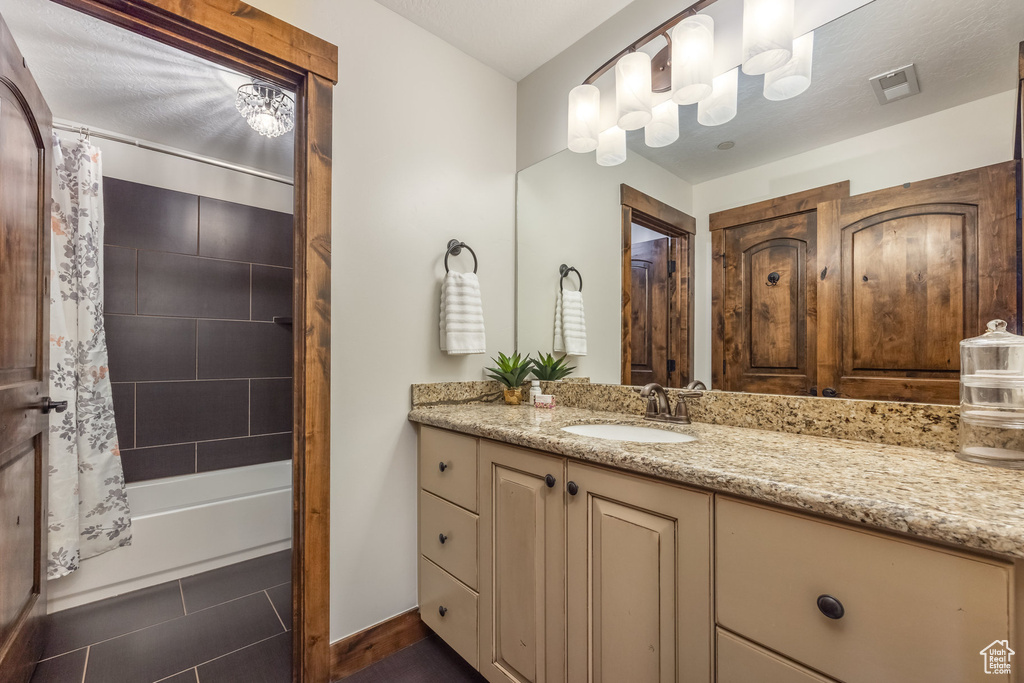 Bathroom with vanity, shower / tub combo, and baseboards