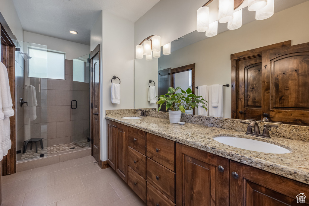Full bathroom with double vanity, a shower stall, and tile patterned flooring