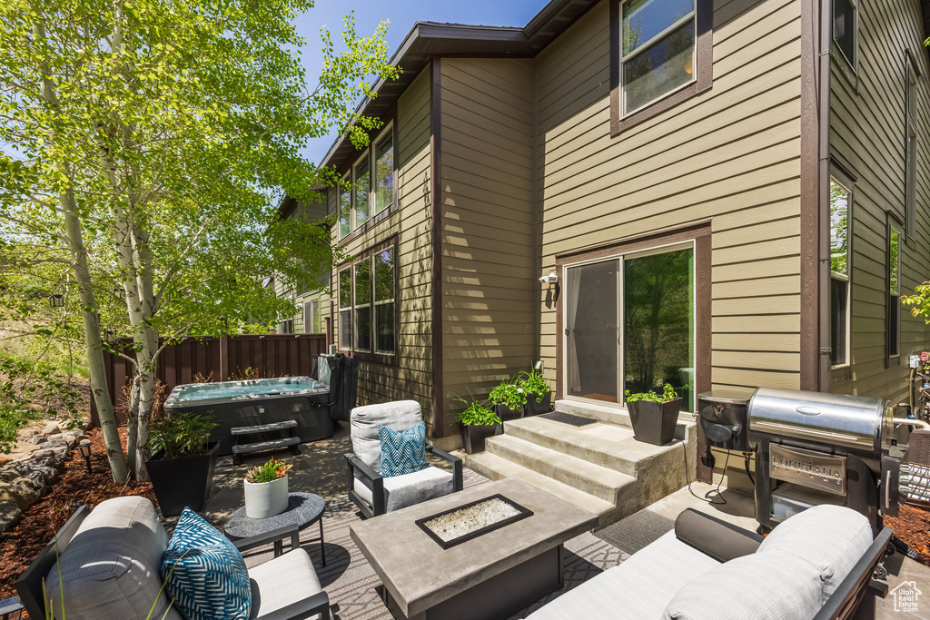 View of patio with a hot tub, an outdoor living space with a fire pit, area for grilling, and entry steps