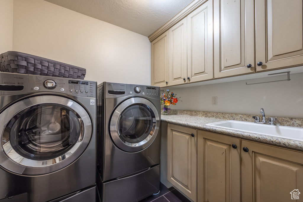 Laundry room with cabinet space, independent washer and dryer, a textured ceiling, and dark tile patterned floors