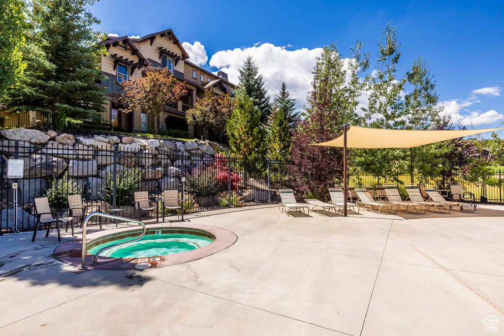 View of swimming pool with a hot tub and a patio